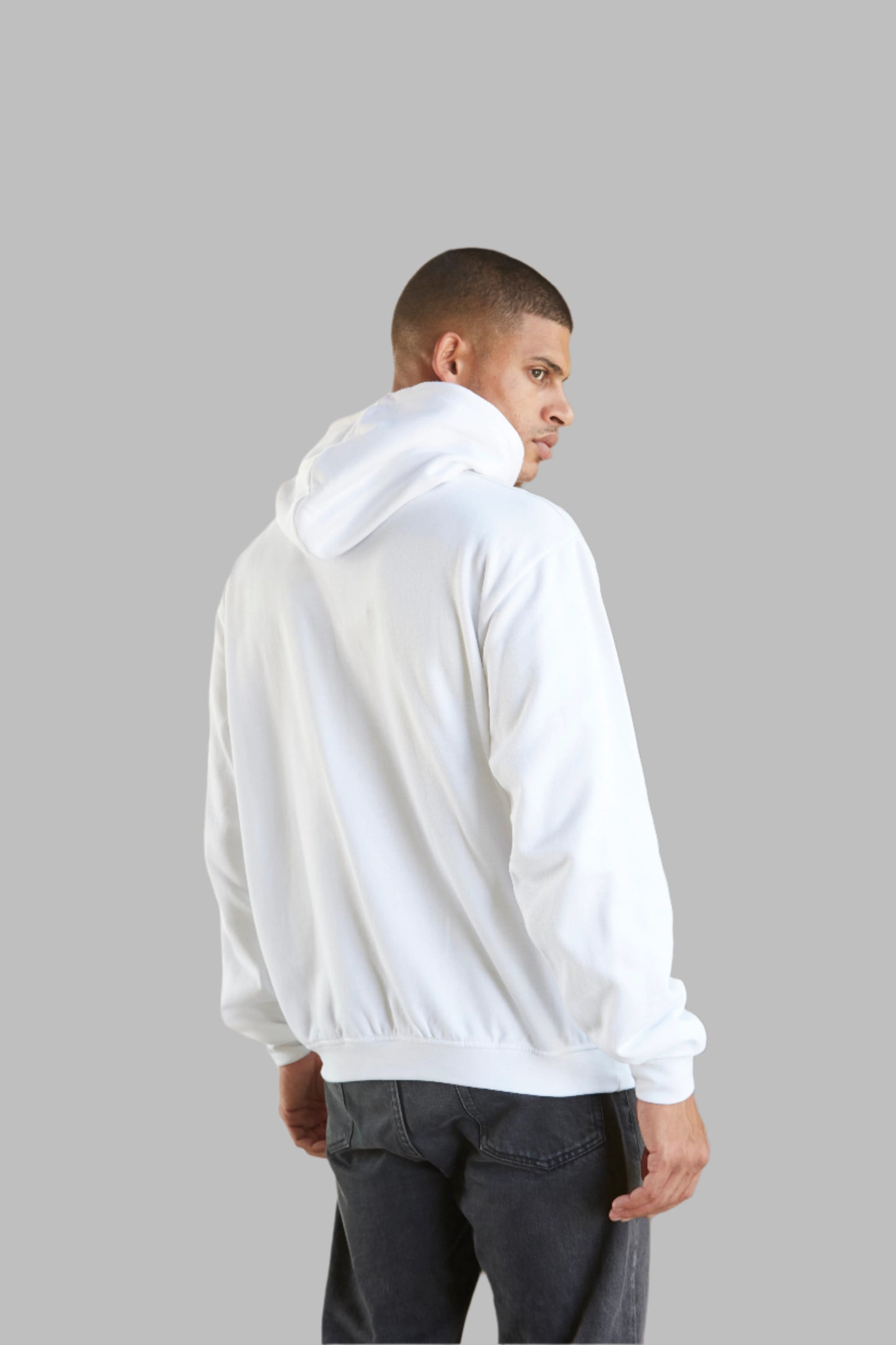 White hoodie with minimalist text and graphic design, worn by a model in a rustic setting. Perfect for casual and stylish wear.